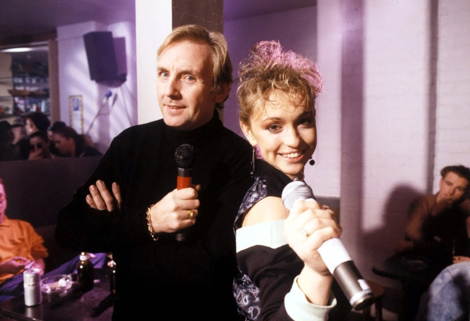 a man stands next to a woman who is holding a microphone