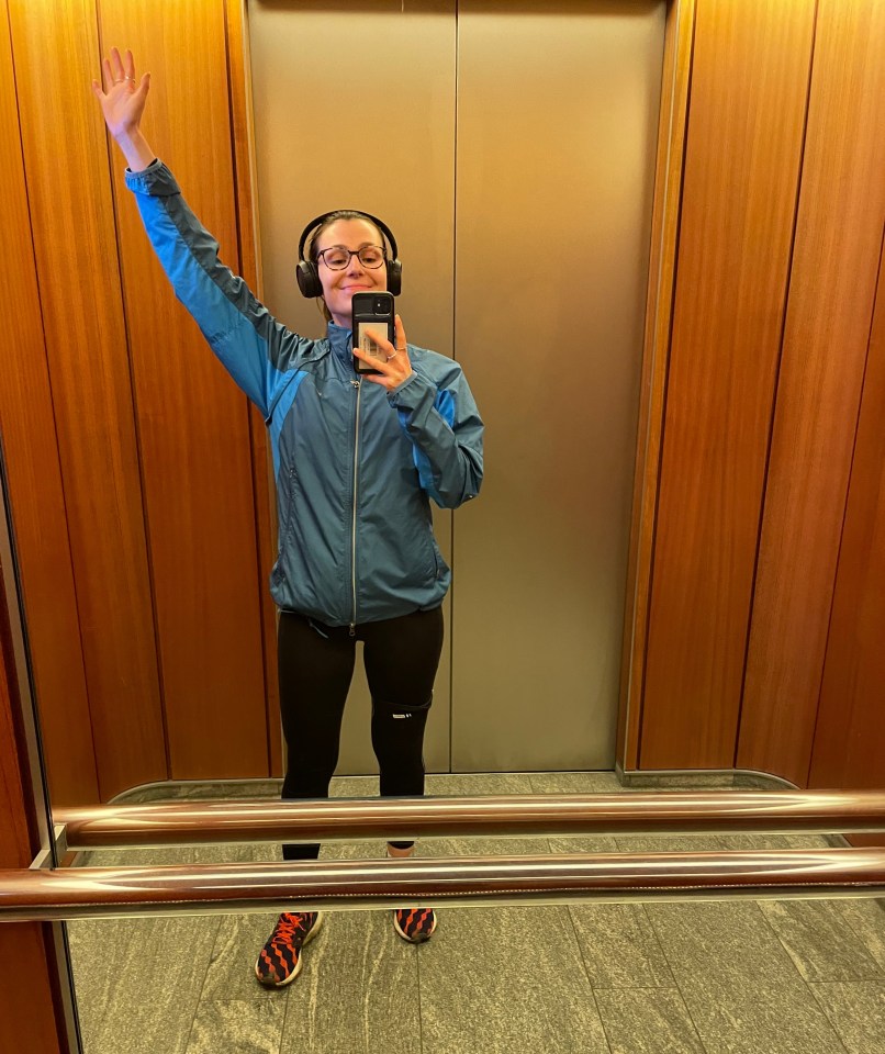 a woman wearing headphones takes a picture of herself in an elevator
