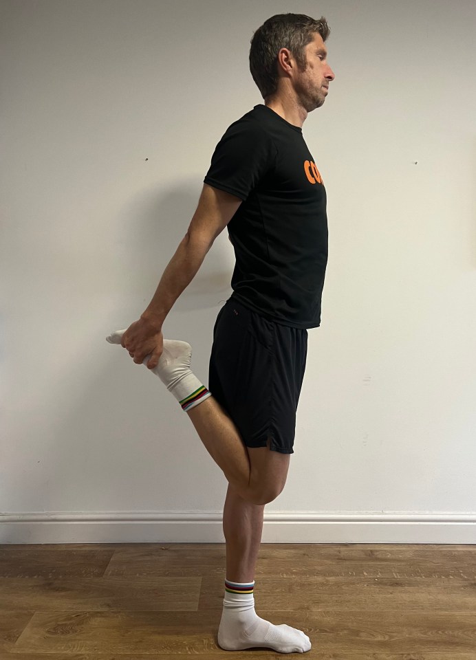 a man wearing a black shirt that says co is stretching his leg