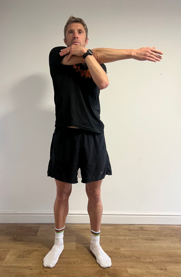 a man wearing a black shirt that says ' snpa ' on it stretches his arms