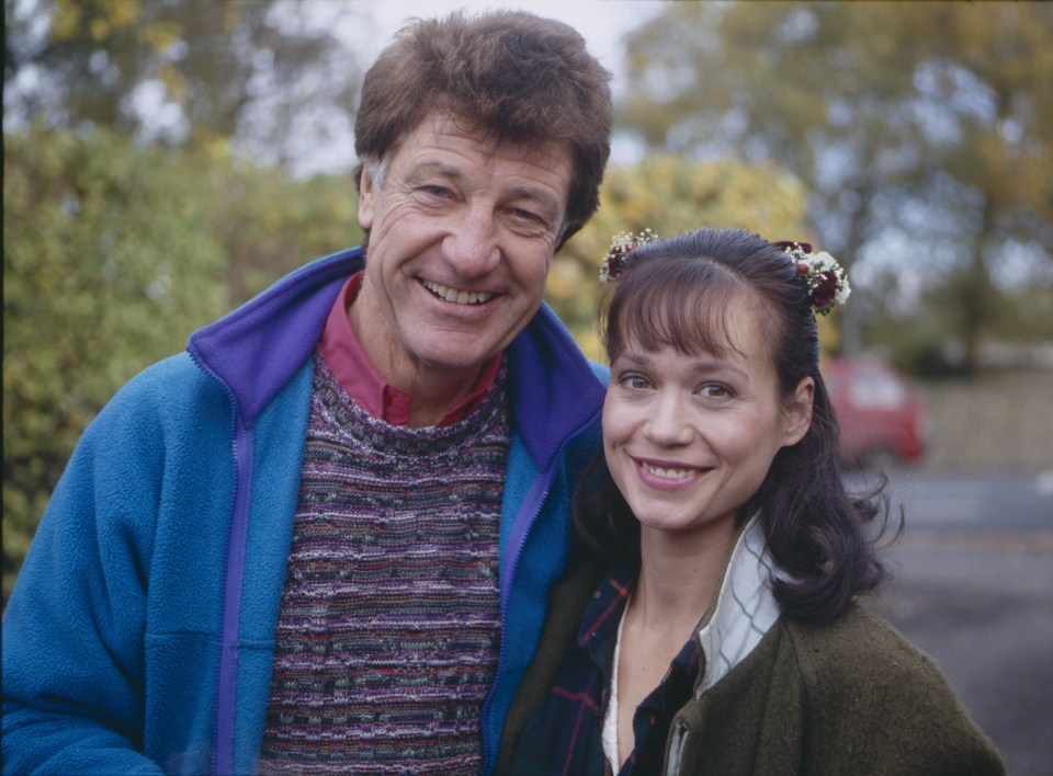 a man and a woman are posing for a picture and the woman has flowers in her hair