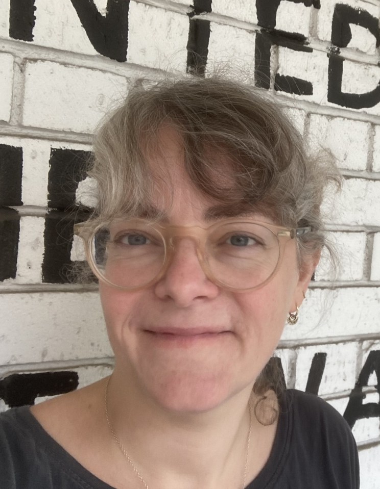a woman wearing glasses is smiling in front of a united sign