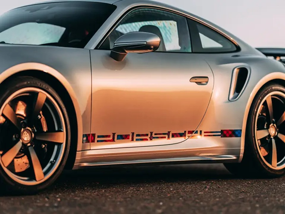 a silver porsche is parked on the side of the road