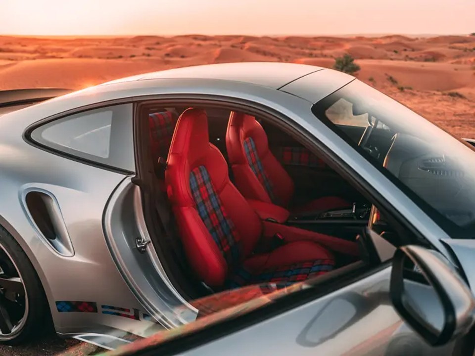a silver sports car with red seats is parked in the desert