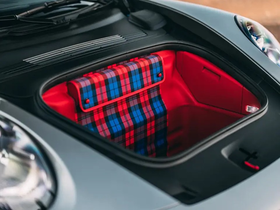 the trunk of a car has a plaid bag in it