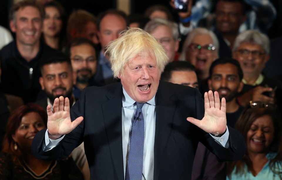 a man in a suit and tie stands in front of a crowd