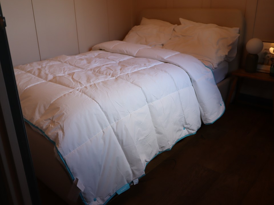 a bed with a white comforter and blue trim