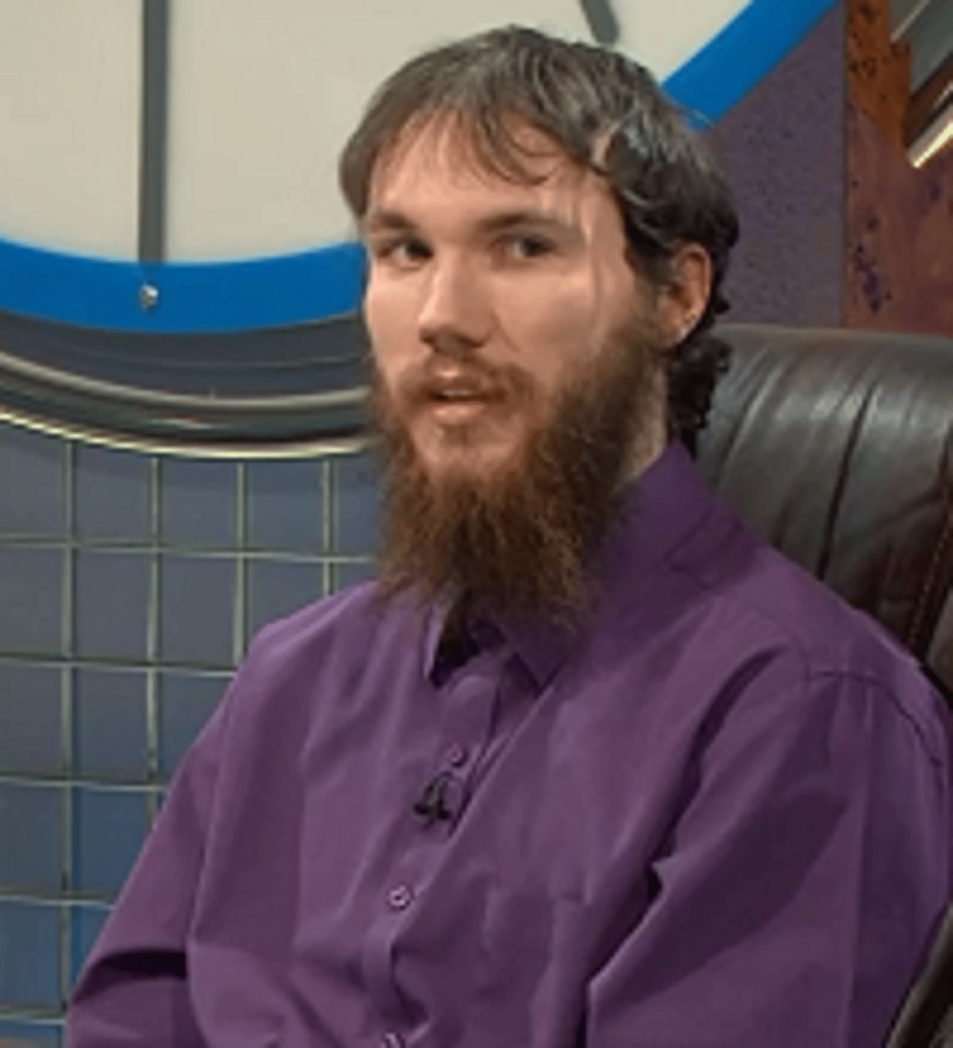a man with a beard is wearing a purple shirt