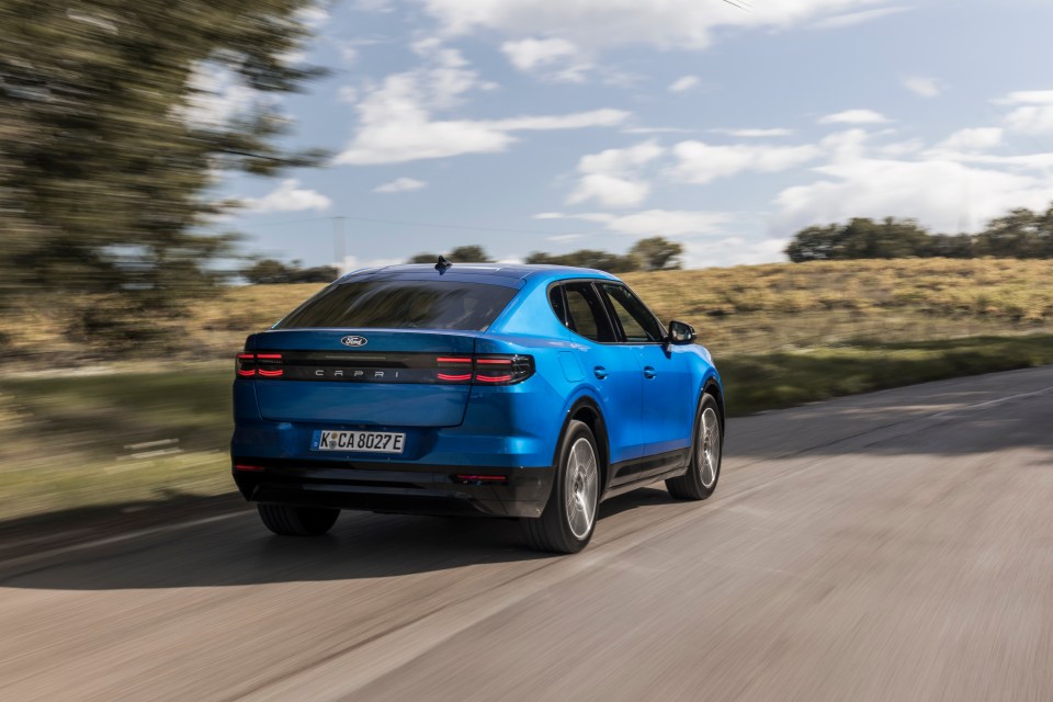 a blue ford car is driving down a road