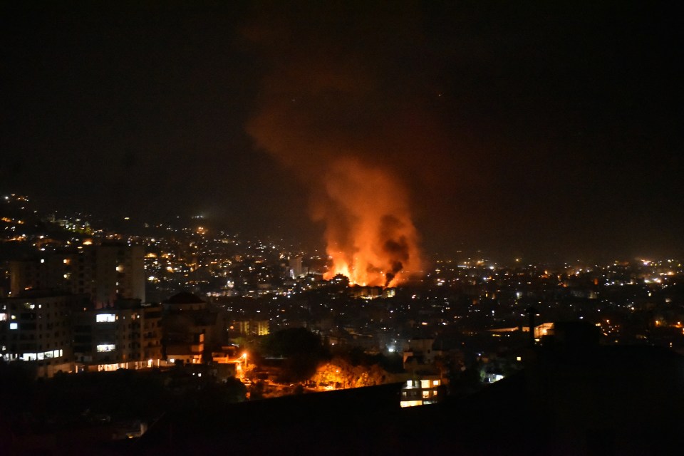 a city at night with smoke coming out of a building