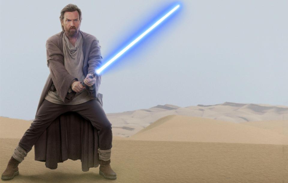 a man holding a blue lightsaber in the desert