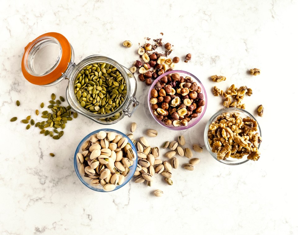 bowls of nuts and seeds including pistachios walnuts and pumpkin seeds