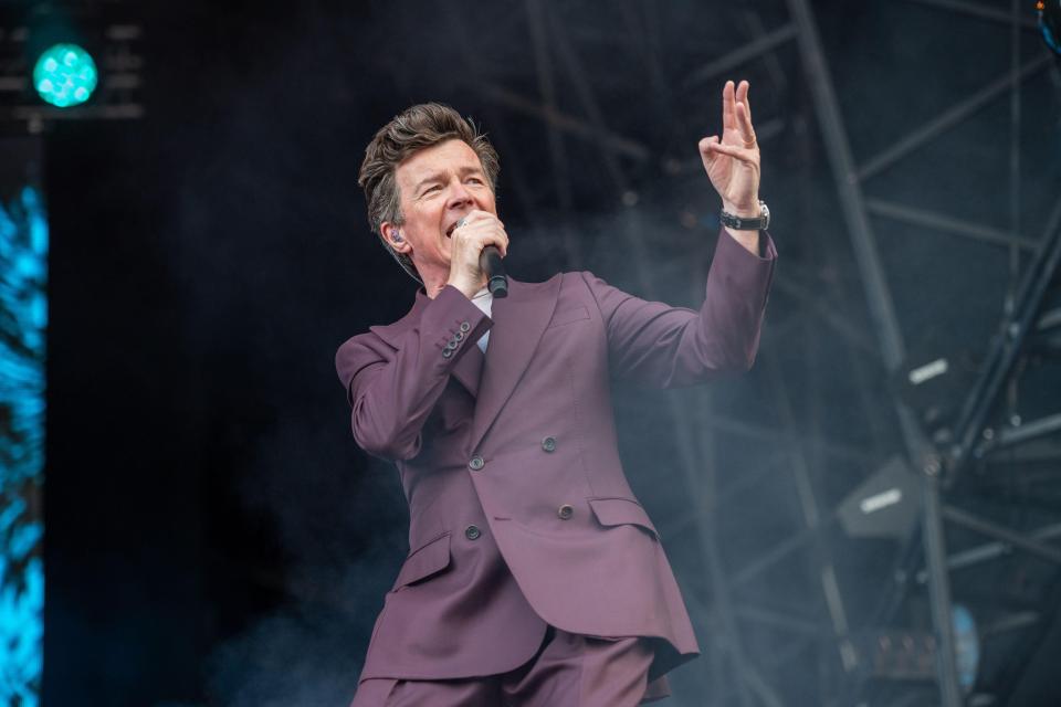 a man in a purple suit singing into a microphone