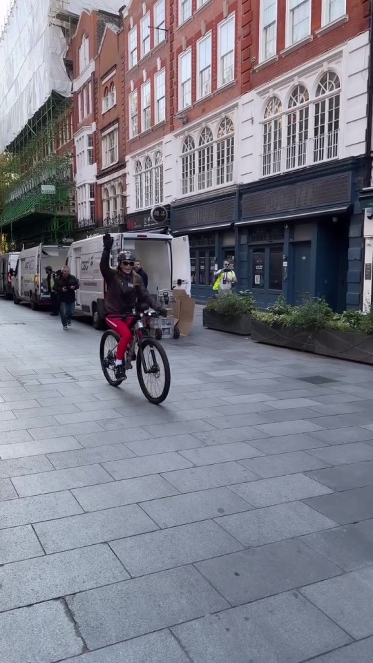 a man is riding a bike down a street in front of a building that says ' emporio ' on it