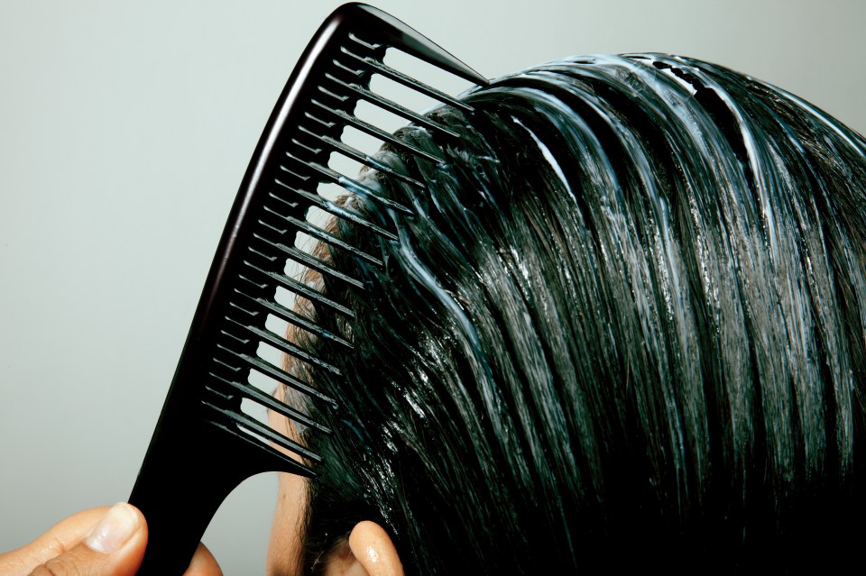a woman combs her hair with a black comb
