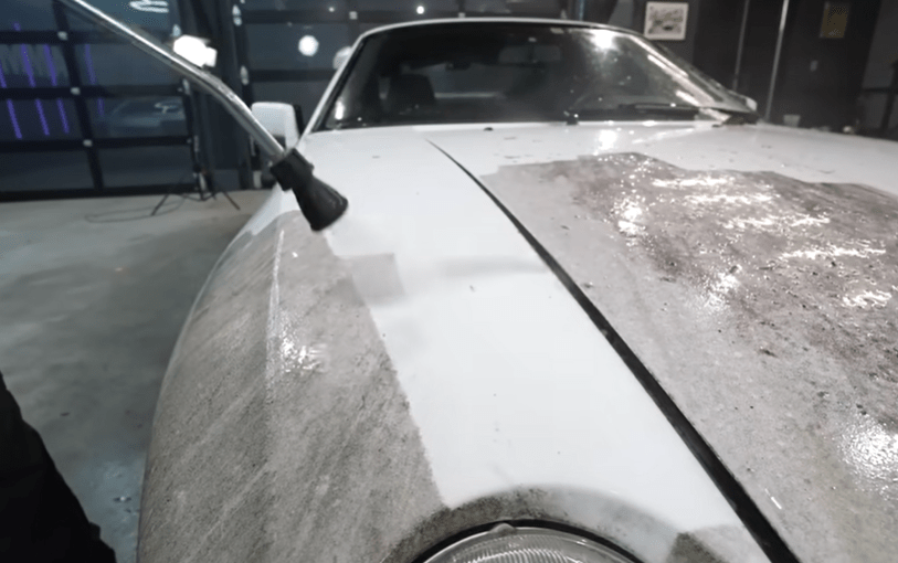 a white car is being cleaned with a high pressure washer
