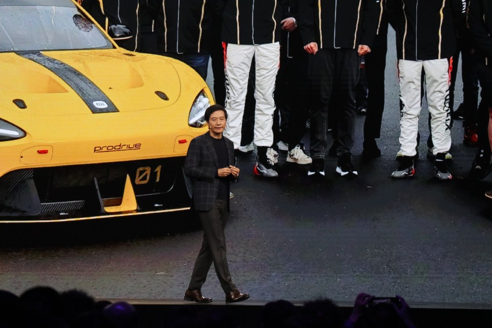 a man stands in front of a yellow prodrive car