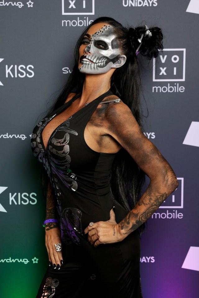 a woman with a skull painted on her face stands in front of a kiss sign