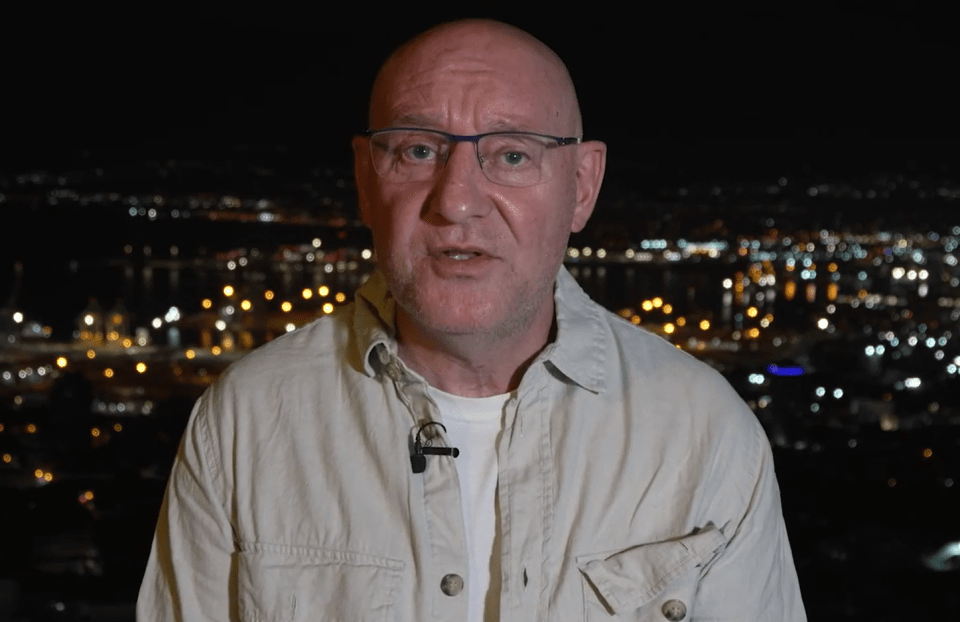 a bald man with glasses and a microphone on his neck