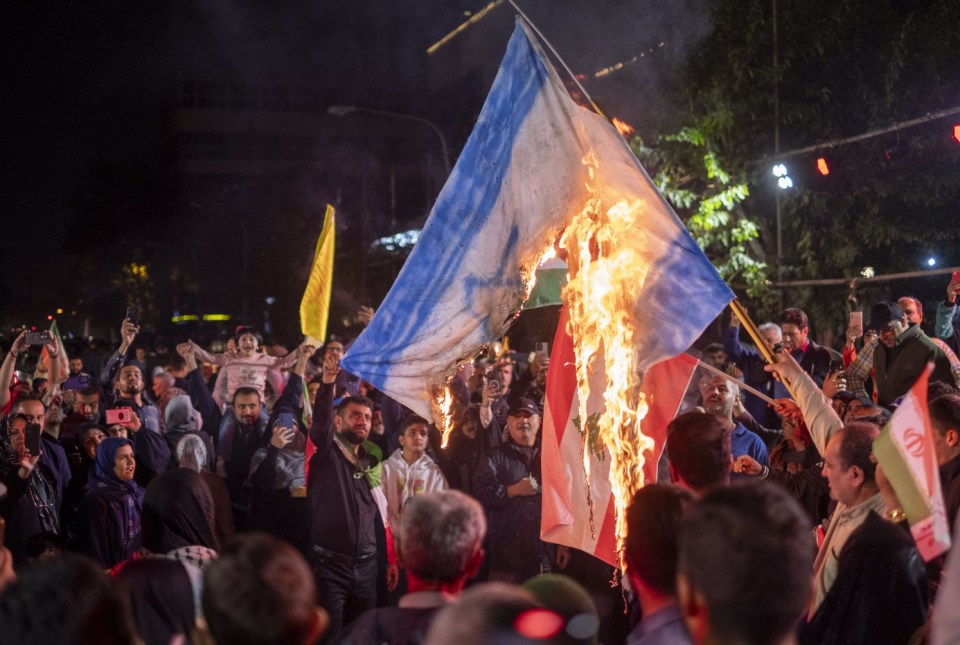Mandatory Credit: Photo by Morteza Nikoubazl/NurPhoto/REX/Shutterstock (14751855j) Iranian protesters shout anti-Israeli slogans while burning an Israeli flag in a celebration for Iran's missile attack against Israel, in Tehran, Iran, on October 1, 2024. Iran launches hundreds of ballistic missiles at Israel in response to the killings of Hamas Leader Esmail Haniyeh in Tehran and Hassan Nasrallah, the Secretary General of Lebanon's Hezbollah, as well as General Abbas Nilforoushan, a commander in the Islamic Revolutionary Guard Corps' (IRGC) Quds Force, in the suburbs of Beirut, Lebanon. Iranians Celebrate Iran's Missile Attack Against Israel, Tehran - 01 Oct 2024