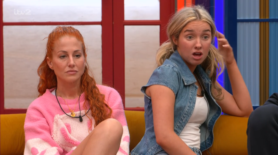 two women are sitting on a couch and one has a surprised look on her face