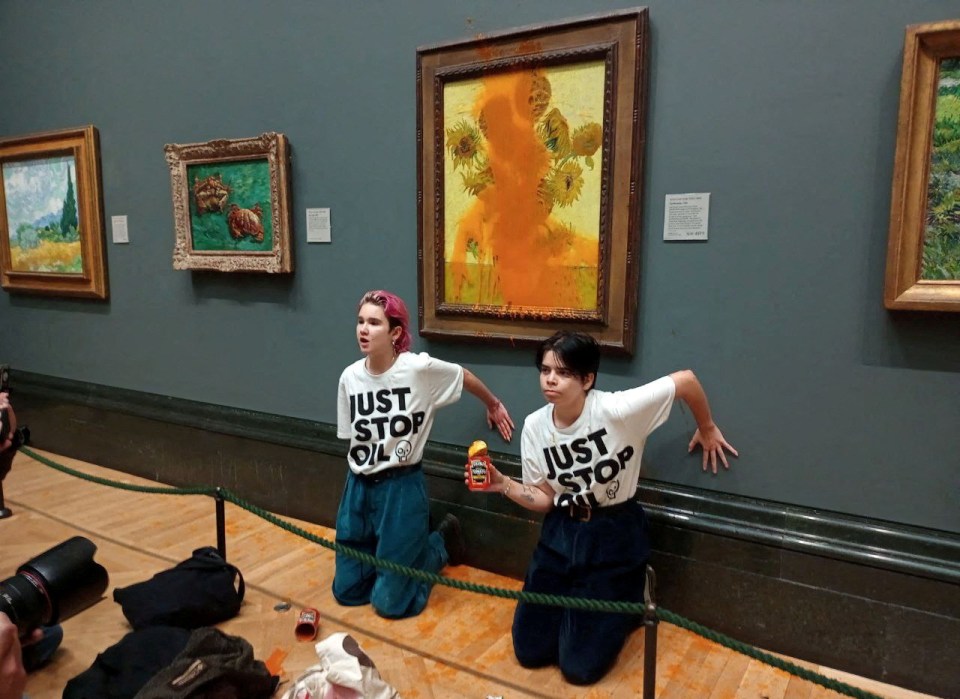 two people wearing shirts that say just stop in front of a painting