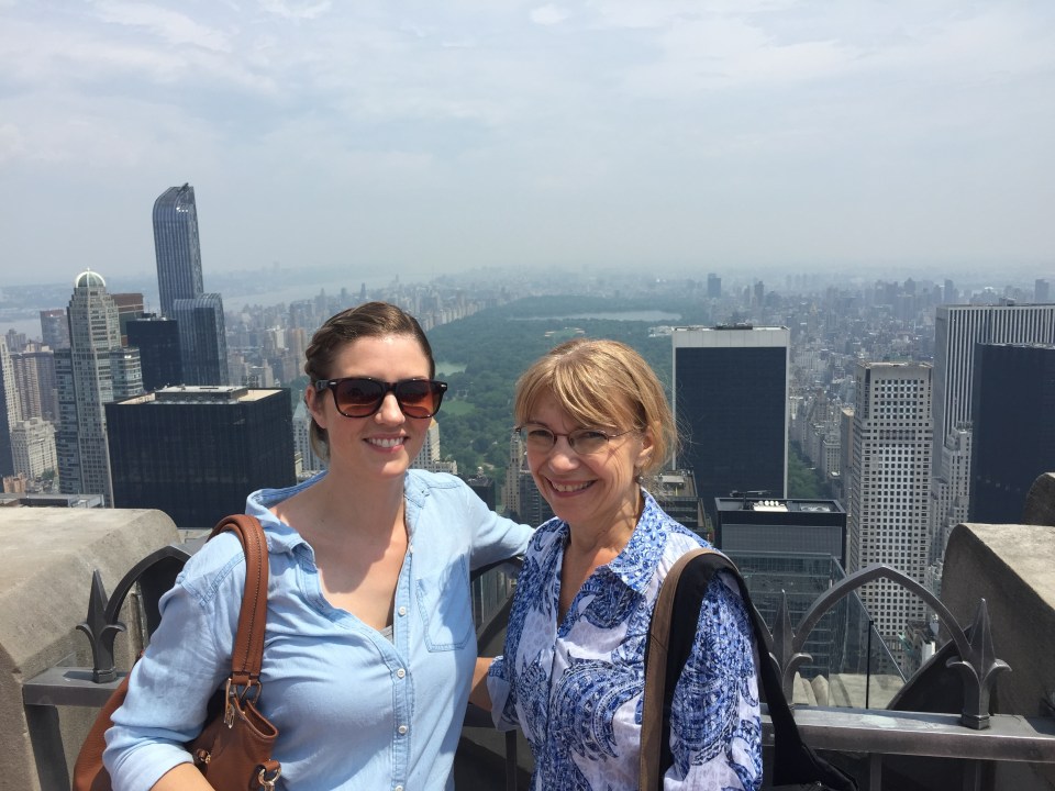 two women are posing for a picture in front of a city skyline