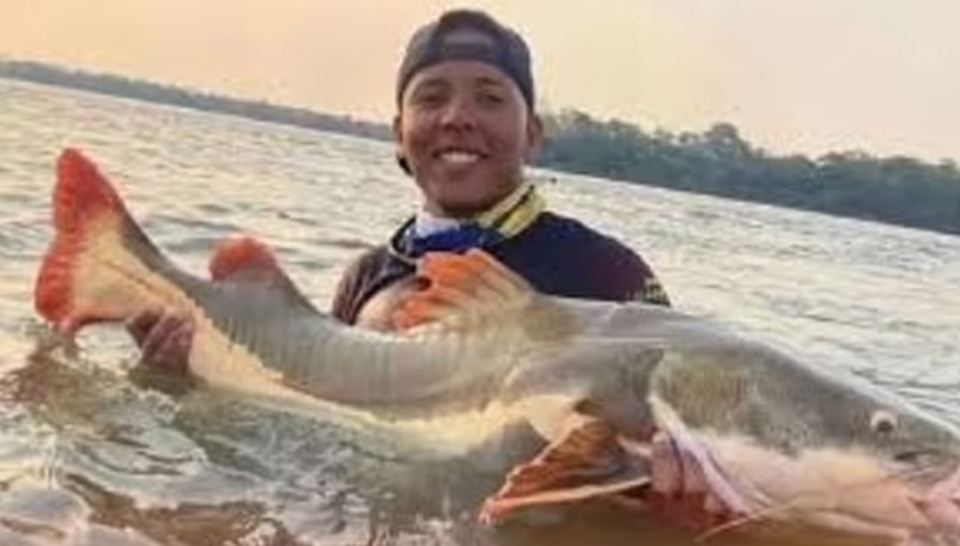 a man is holding a large fish in the water .