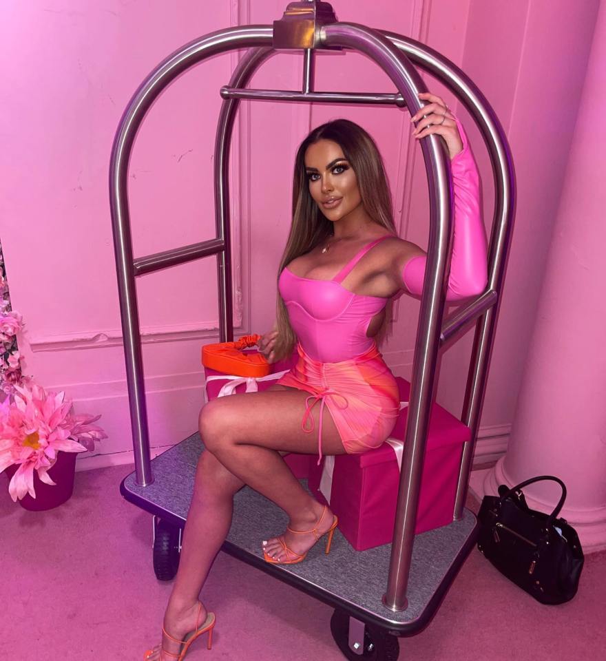 a woman in a pink outfit sits on a luggage cart