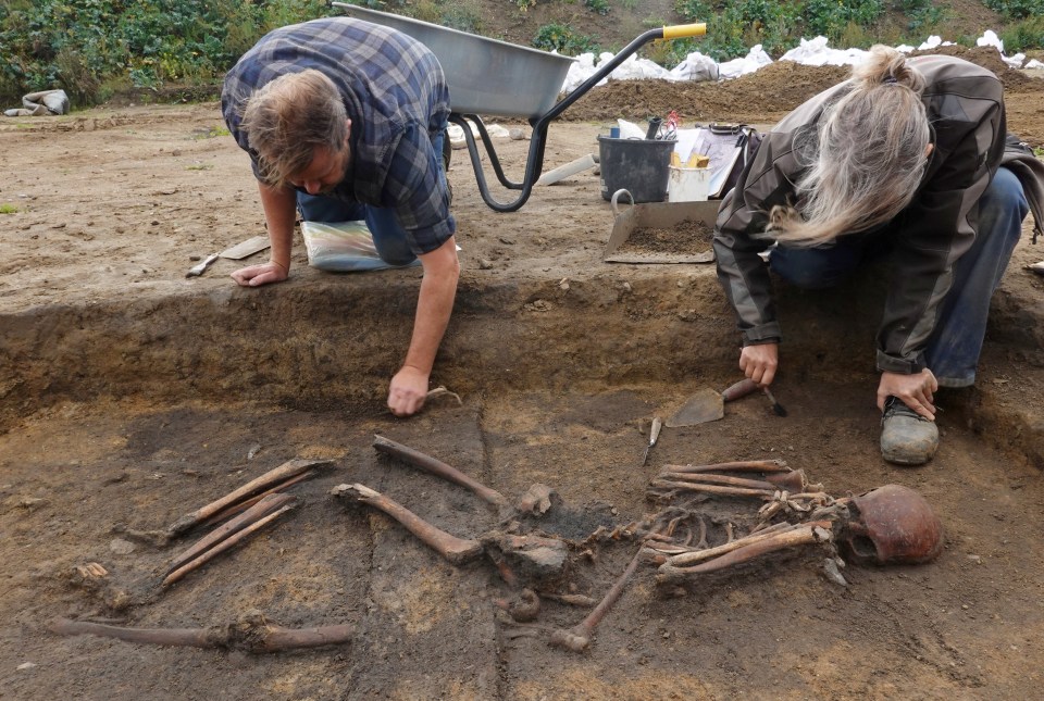 two people are working on a skeleton in the dirt