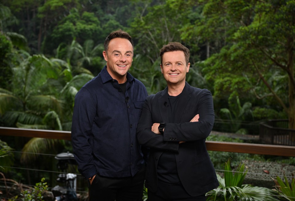 two men standing next to each other with trees in the background