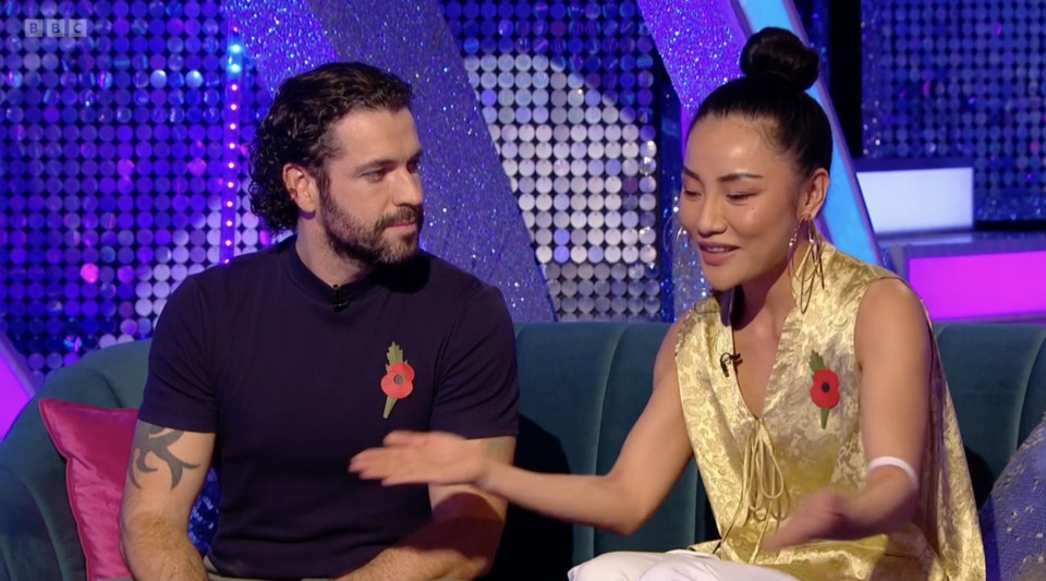 a man with a poppy on his shirt sits next to a woman