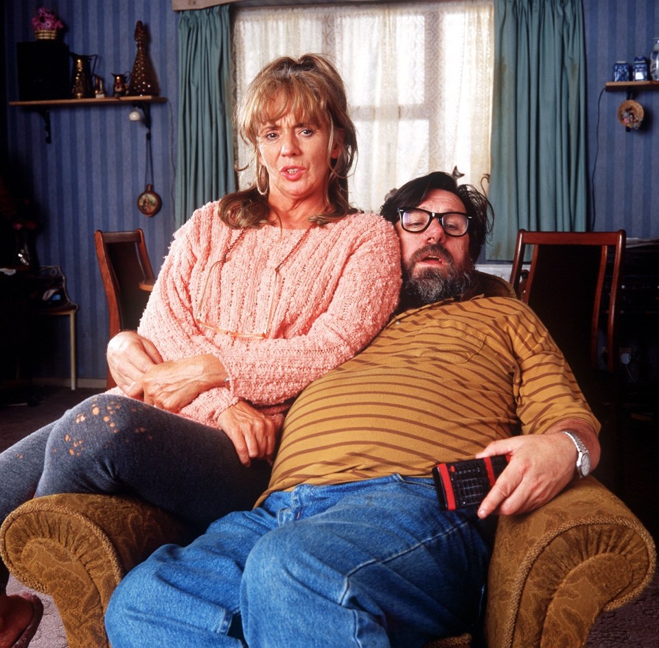 a woman in a pink sweater sits next to a man in a brown shirt