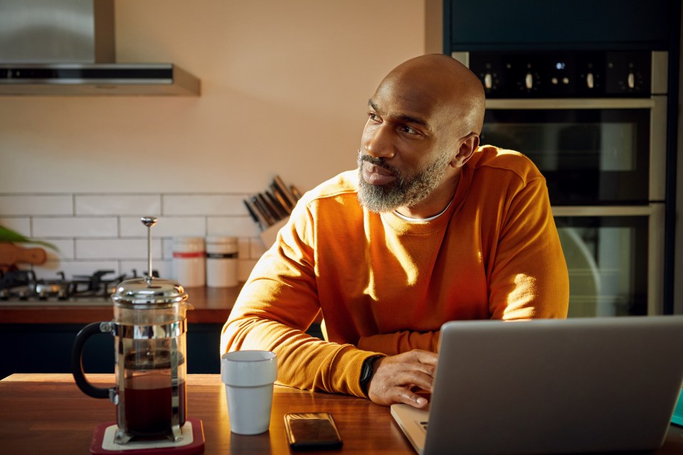 a man sits at a table with a laptop and a cup of coffee