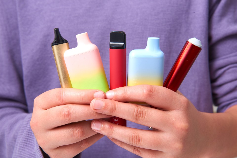 a person is holding a variety of electronic cigarettes in their hands