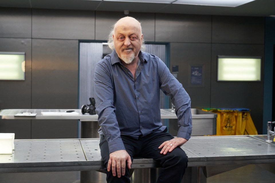 a man in a blue shirt sits on a metal table