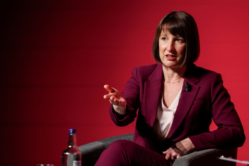 a woman in a purple suit is sitting in front of a red wall