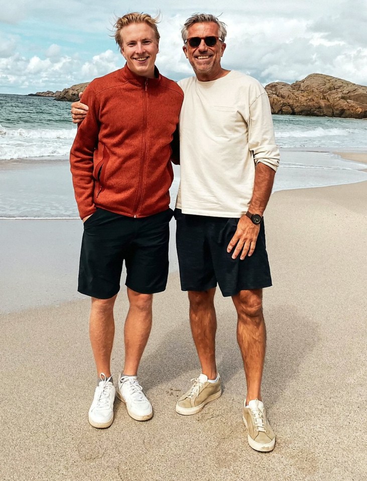 two men standing on a beach with one wearing sunglasses