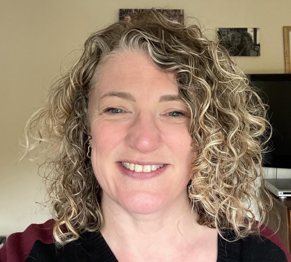 a woman with curly hair smiles for the camera