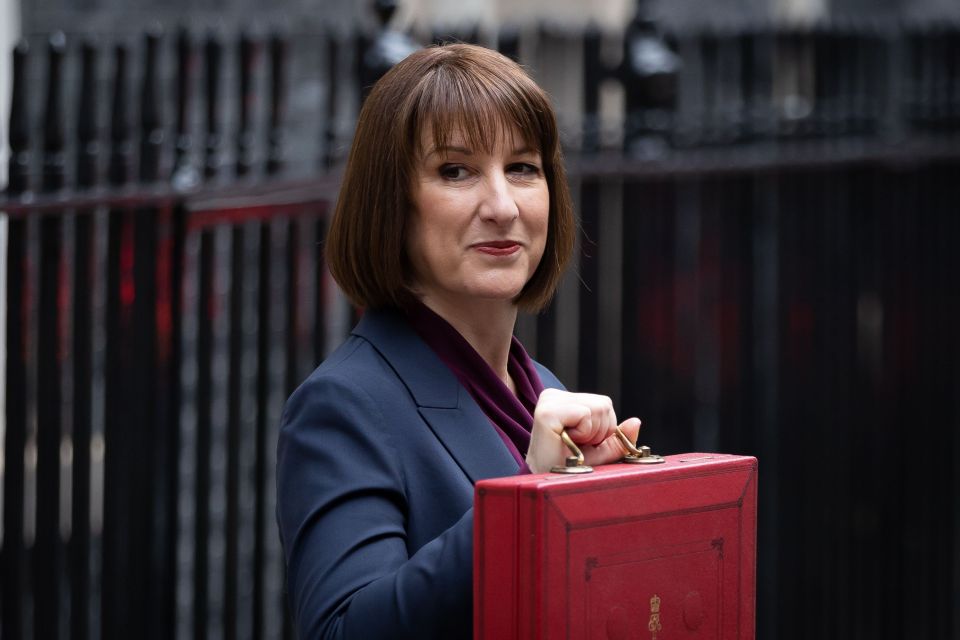 a woman in a suit holds a red briefcase that says ' uk ' on it