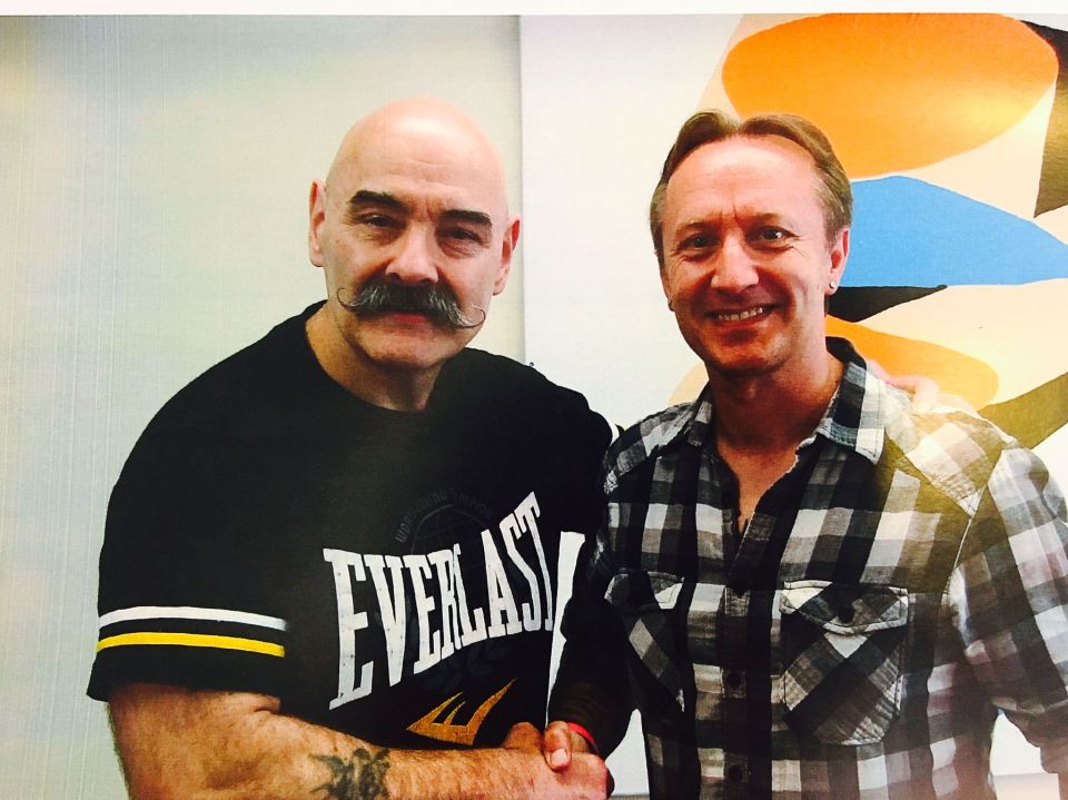 a man wearing an everlast shirt shakes hands with another man