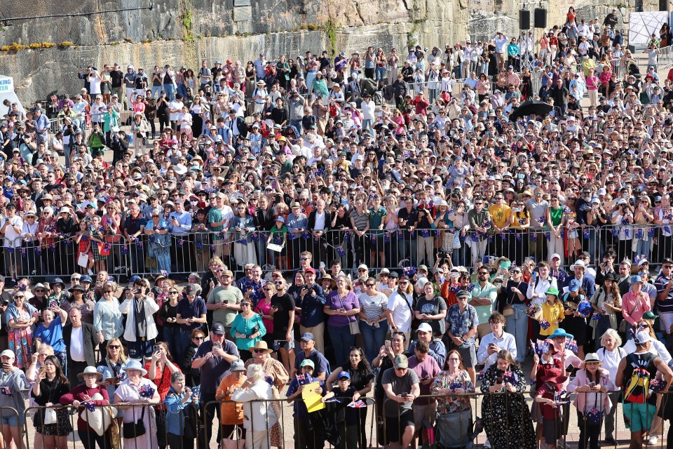 a large crowd of people are gathered in front of a fence