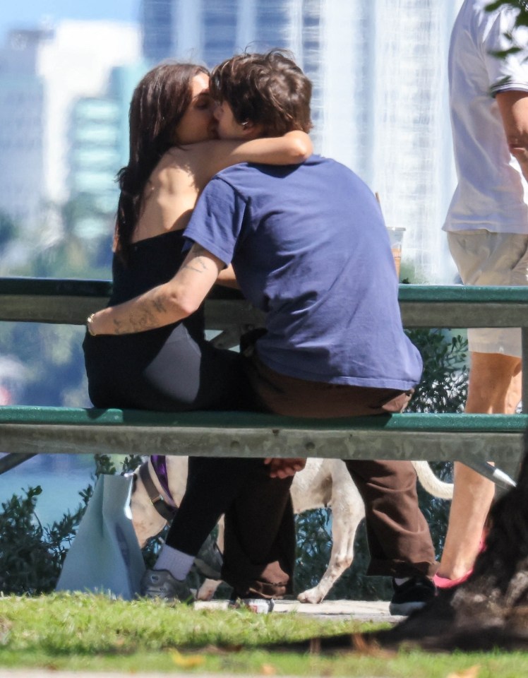 a man and a woman are kissing on a park bench