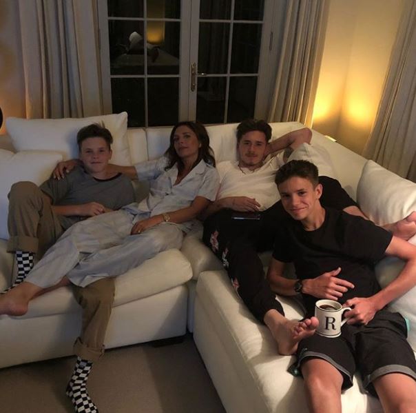 a family is sitting on a couch with a mug that has the letter r on it