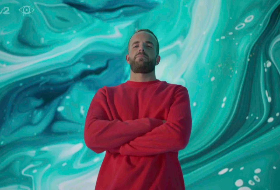 a man in a red sweater stands with his arms crossed in front of a itv2 logo