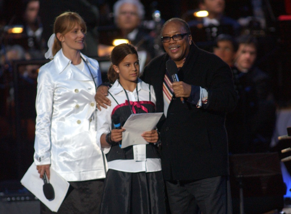 a man holding a microphone stands next to a woman and a girl