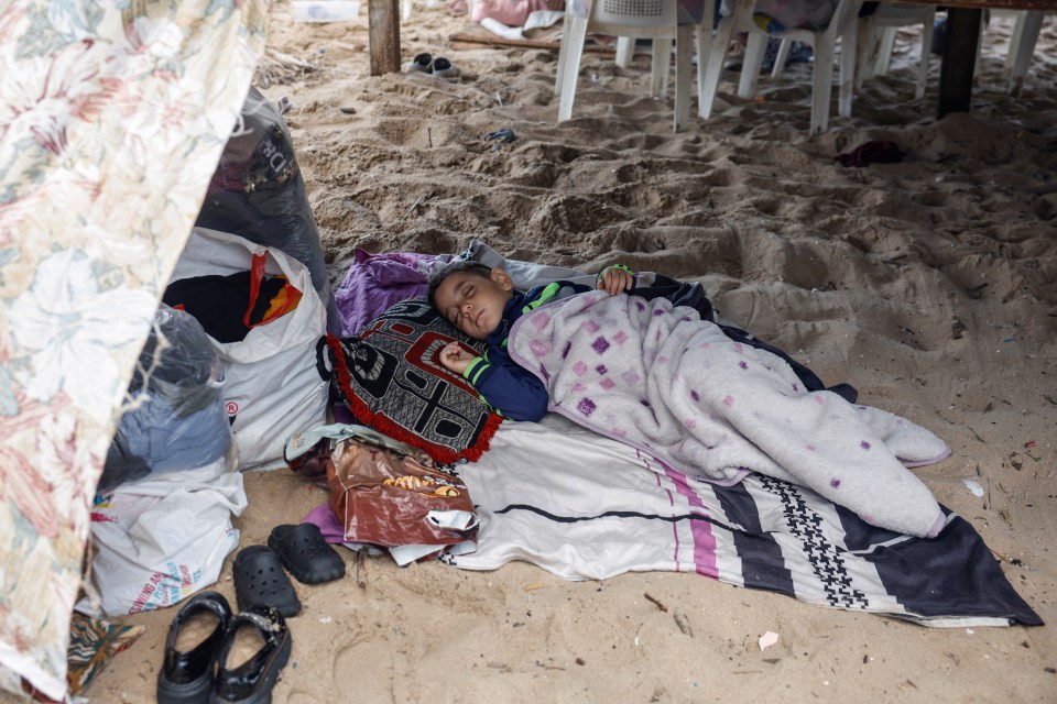 A  child sleeps at a makeshift encampment after a series of Israeli airstrikes