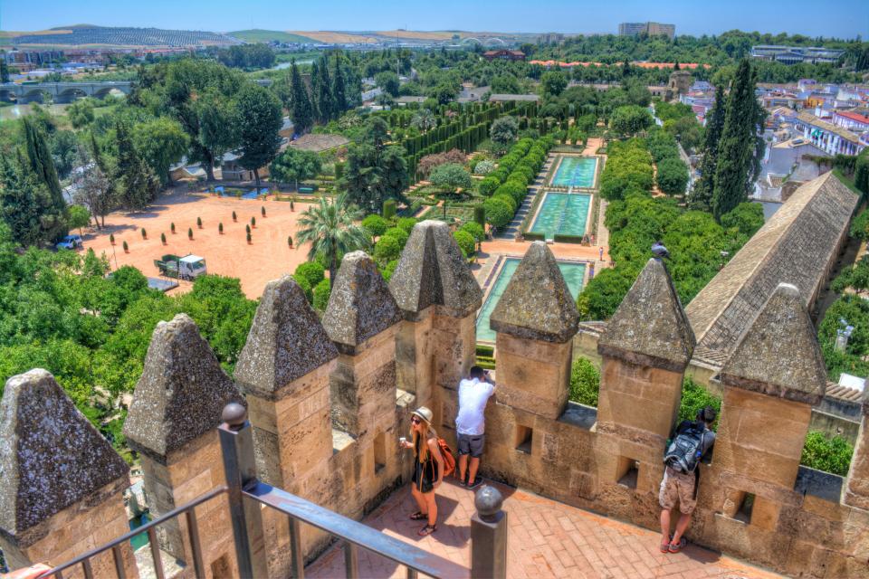 a couple of people standing on a balcony overlooking a garden