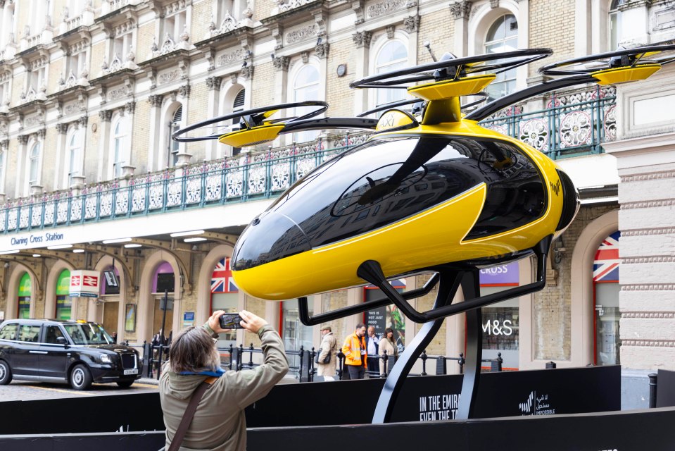 a person taking a picture of a helicopter in front of a m & s store