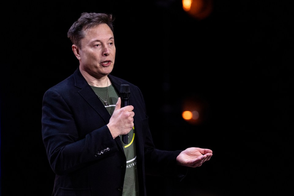 elon musk speaking into a microphone in a dark room